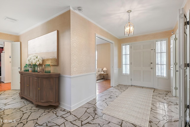 foyer with ornamental molding and a chandelier