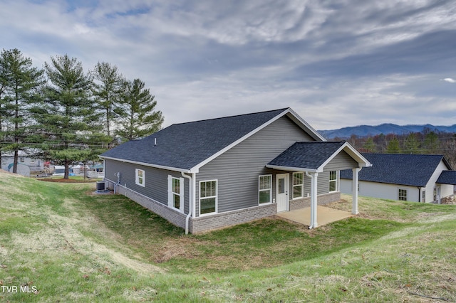 back of house featuring a mountain view, cooling unit, and a lawn