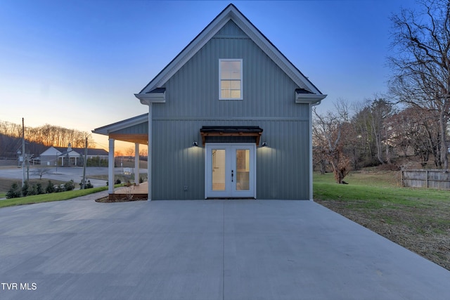 back house at dusk with a lawn and french doors