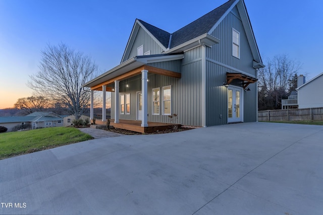 property exterior at dusk featuring a porch and a yard