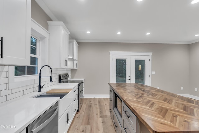 kitchen with butcher block counters, light wood-type flooring, tasteful backsplash, white cabinetry, and stainless steel appliances