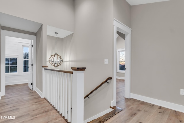 hallway with a healthy amount of sunlight, a notable chandelier, and light hardwood / wood-style floors