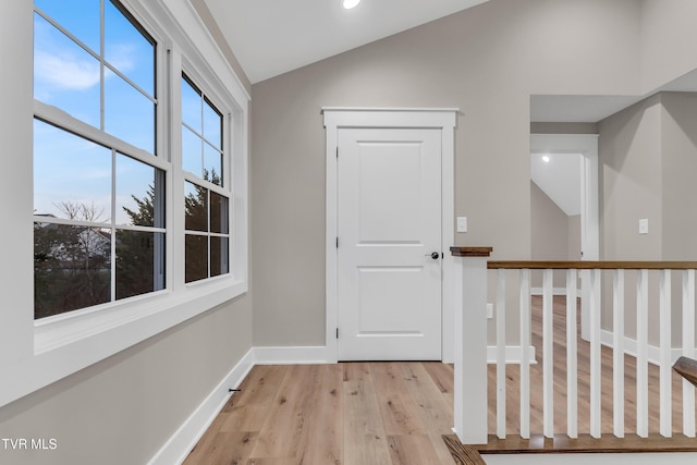 corridor with light hardwood / wood-style flooring and lofted ceiling