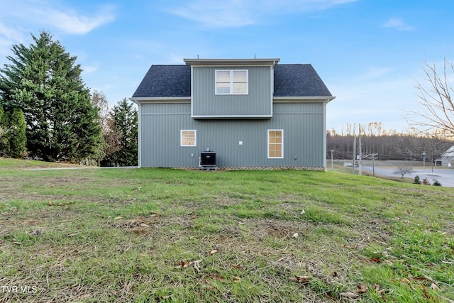 back of property with central AC and a lawn