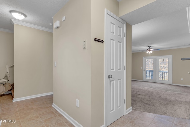 hall featuring a textured ceiling, light colored carpet, and crown molding