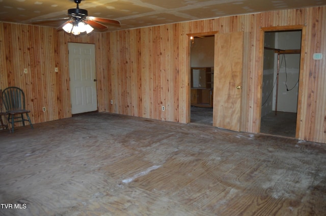 spare room with ceiling fan and wooden walls