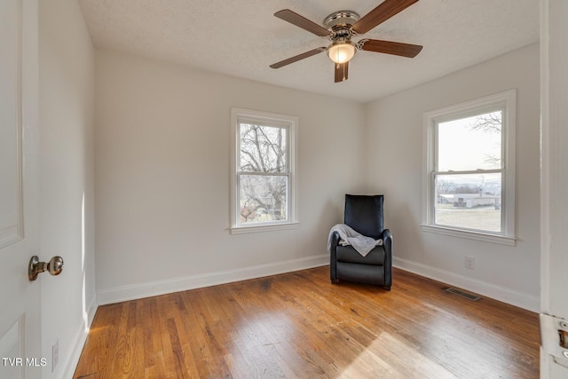 unfurnished room featuring visible vents, a ceiling fan, a textured ceiling, light wood-type flooring, and baseboards