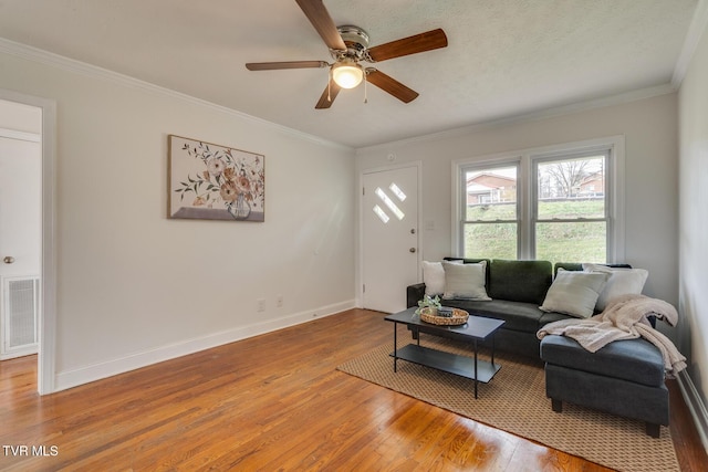 living room with light wood-type flooring, baseboards, visible vents, and ornamental molding