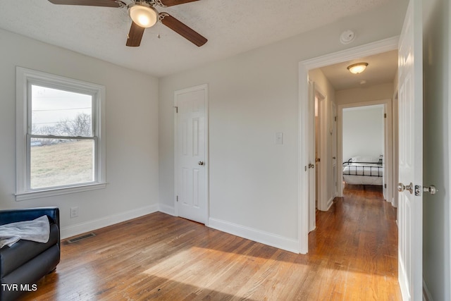 sitting room featuring light wood-style flooring, visible vents, and baseboards