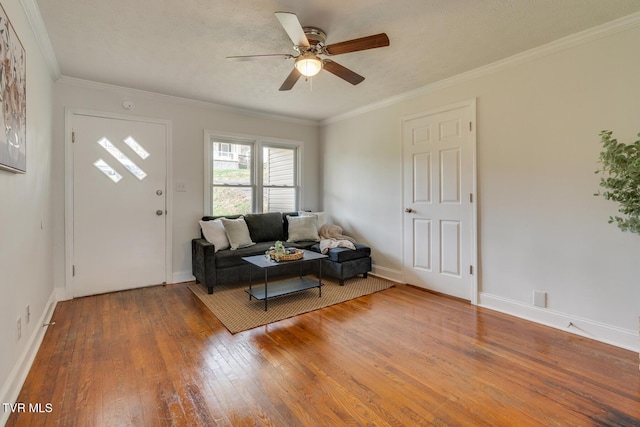 living area featuring ceiling fan, crown molding, baseboards, and hardwood / wood-style flooring