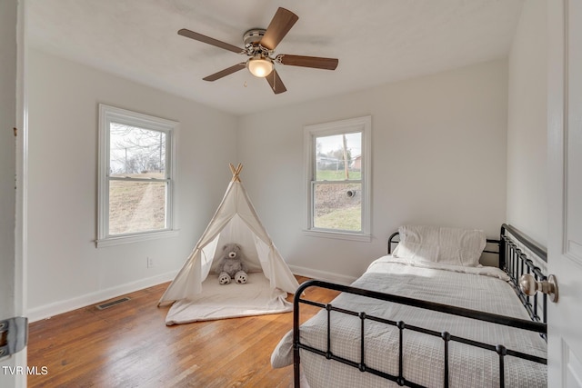 bedroom with baseboards, visible vents, ceiling fan, and wood finished floors