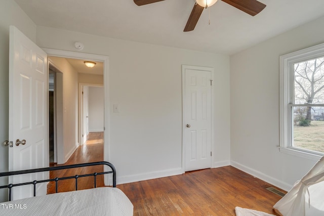 bedroom with ceiling fan, wood finished floors, visible vents, and baseboards