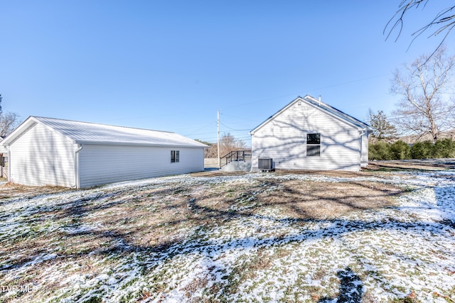 snow covered back of property featuring central AC unit