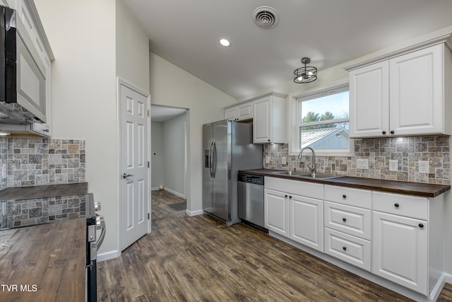 kitchen with white cabinets, tasteful backsplash, appliances with stainless steel finishes, and wooden counters