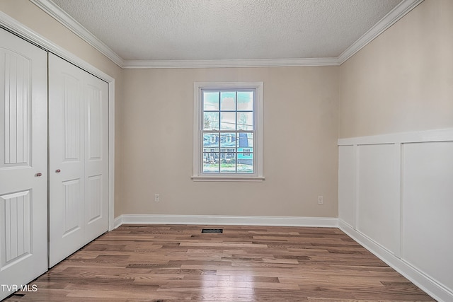 unfurnished bedroom featuring crown molding, a textured ceiling, and hardwood / wood-style flooring