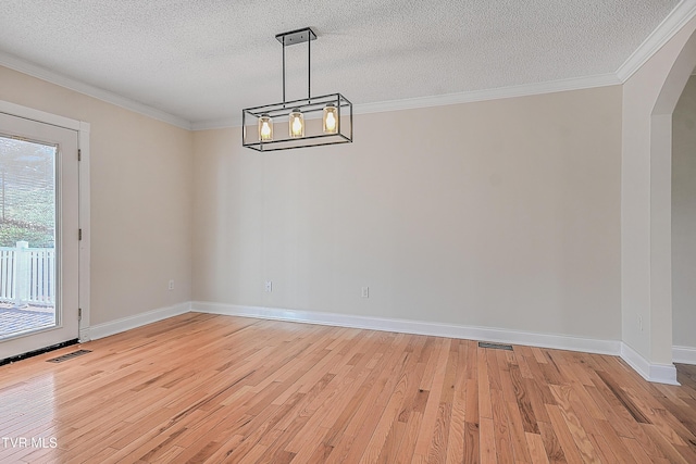 unfurnished dining area with a textured ceiling, light hardwood / wood-style floors, and ornamental molding