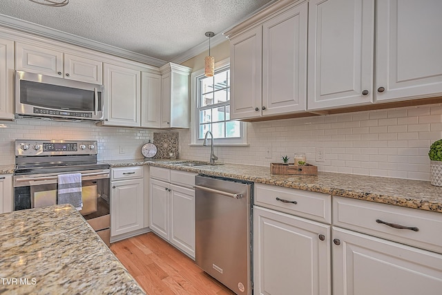 kitchen with a textured ceiling, stainless steel appliances, white cabinetry, and sink