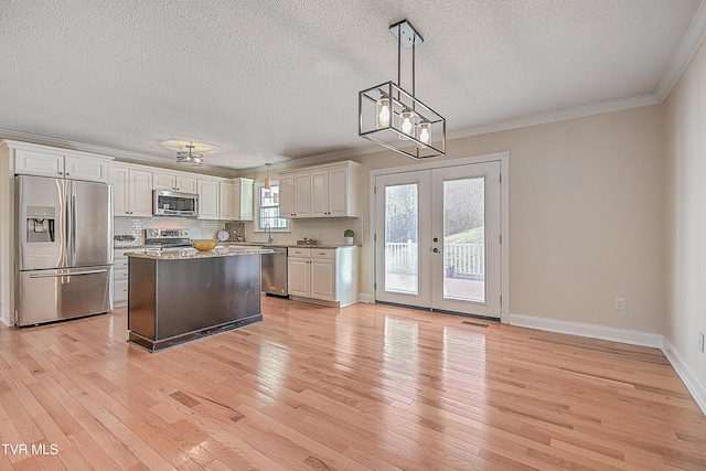 kitchen featuring white cabinets, a textured ceiling, appliances with stainless steel finishes, decorative light fixtures, and light hardwood / wood-style floors