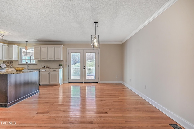 interior space with french doors, light wood-type flooring, a wealth of natural light, and ornamental molding