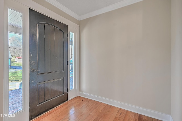 entrance foyer with a wealth of natural light, crown molding, and light hardwood / wood-style floors