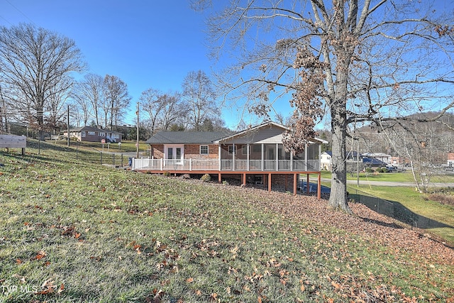 back of property with a sunroom, a yard, and a wooden deck