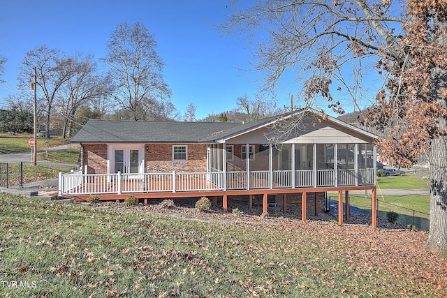 rear view of property featuring a sunroom, a deck, and a yard