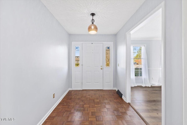 foyer featuring dark parquet flooring and a textured ceiling