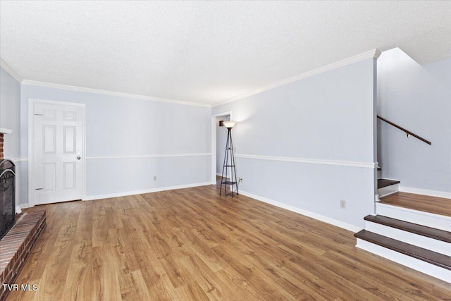 unfurnished living room featuring hardwood / wood-style flooring, crown molding, a textured ceiling, and a brick fireplace