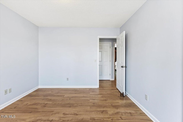 empty room with hardwood / wood-style floors and a textured ceiling