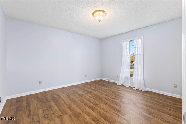 empty room featuring dark hardwood / wood-style flooring and a textured ceiling