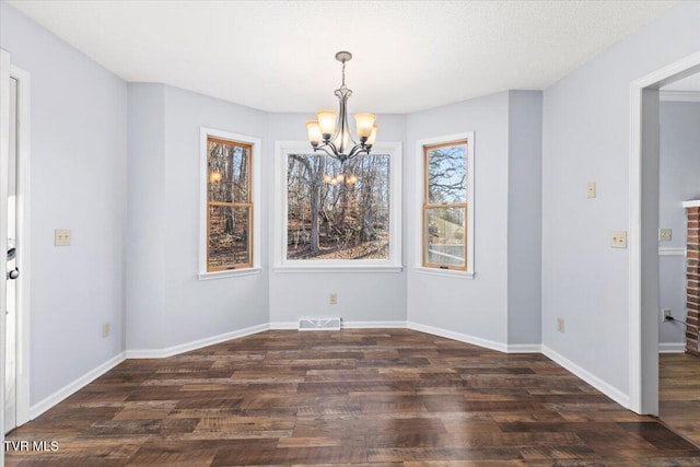 unfurnished dining area featuring dark wood-type flooring and a notable chandelier