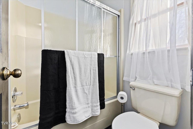 bathroom with shower / bath combination with glass door and toilet