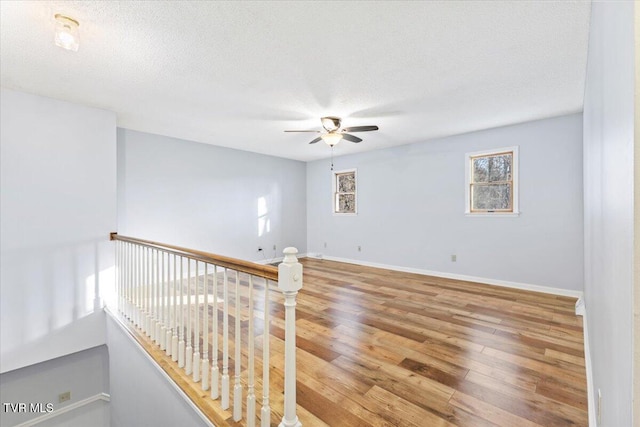 unfurnished room with ceiling fan, a textured ceiling, and hardwood / wood-style flooring