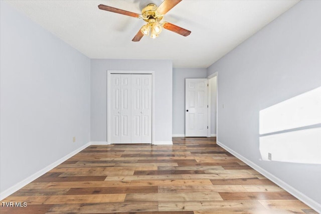 unfurnished bedroom featuring hardwood / wood-style floors, a closet, and ceiling fan