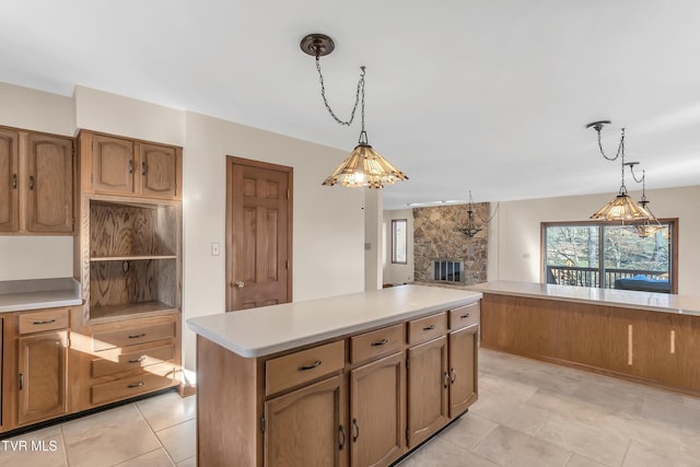 kitchen with a stone fireplace, a kitchen island, light tile patterned flooring, and decorative light fixtures