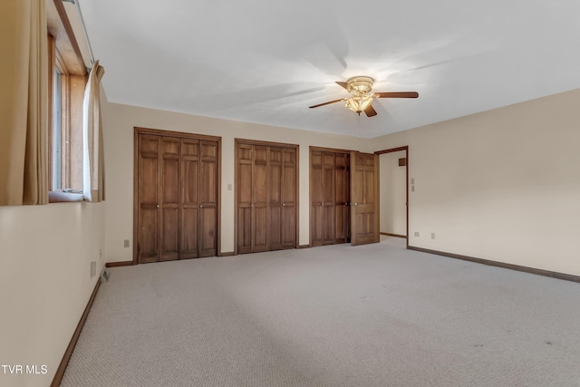 unfurnished bedroom featuring ceiling fan, carpet floors, and two closets