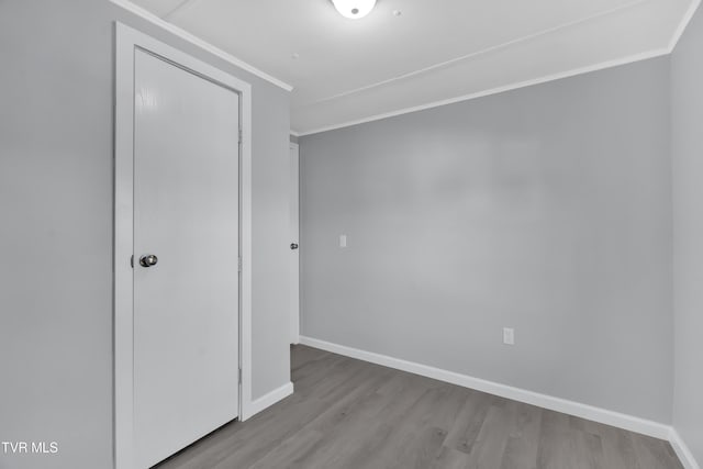 unfurnished bedroom featuring a closet, crown molding, and light hardwood / wood-style flooring