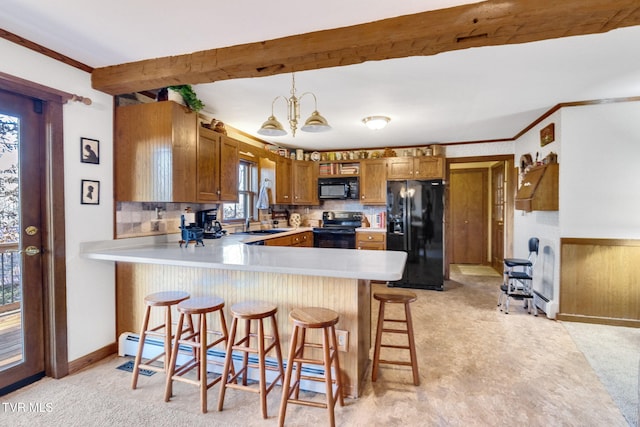 kitchen featuring black appliances, an inviting chandelier, beamed ceiling, hanging light fixtures, and a breakfast bar area