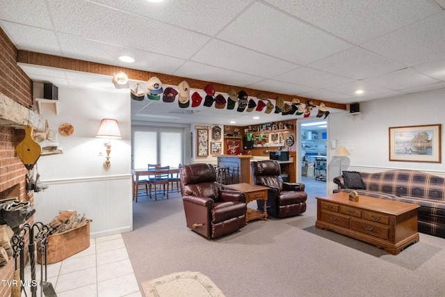 living room featuring a brick fireplace, tile patterned floors, and a drop ceiling