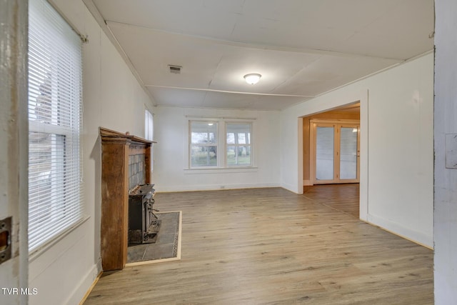 unfurnished living room featuring light wood-type flooring and a wood stove