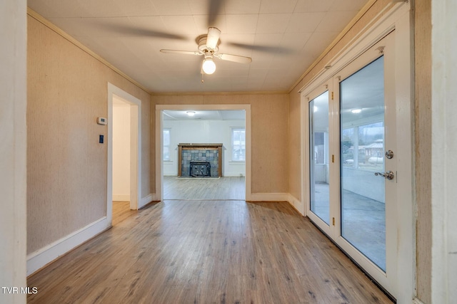 unfurnished living room featuring light hardwood / wood-style floors, a wealth of natural light, ornamental molding, and ceiling fan