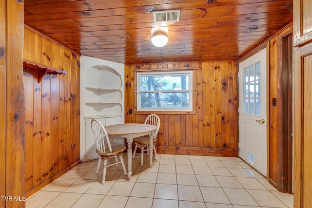 dining space featuring wooden walls, wooden ceiling, and light tile patterned floors