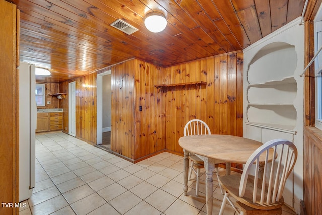 dining area with wooden walls, light tile patterned floors, and wood ceiling