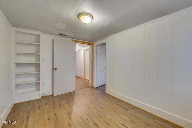 unfurnished bedroom with wooden walls and light hardwood / wood-style flooring