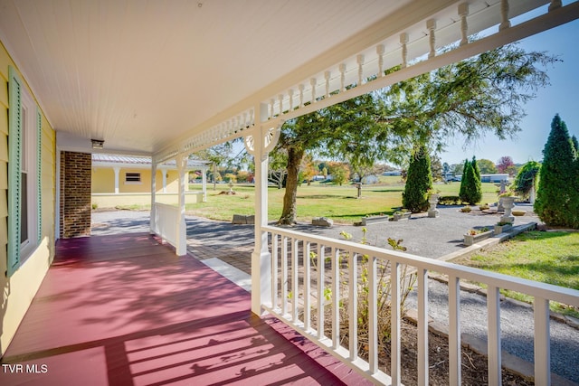 wooden terrace with a yard and covered porch