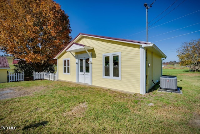 rear view of house featuring central AC and a yard