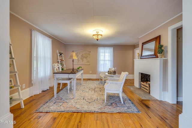 office space featuring crown molding, hardwood / wood-style floors, and a brick fireplace