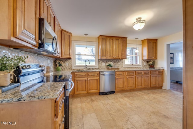 kitchen featuring pendant lighting, sink, decorative backsplash, light stone countertops, and appliances with stainless steel finishes