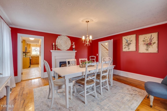 dining area featuring hardwood / wood-style flooring, ornamental molding, sink, and a chandelier