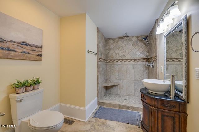 bathroom with tiled shower, vanity, toilet, and tile patterned flooring